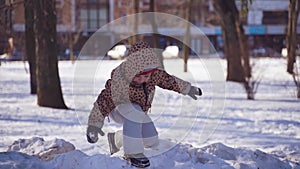 Caucasian happy preschool girl plays with snow on a sunny winter day in a park