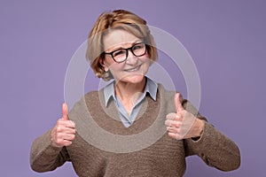 Caucasian happy senior woman showing her two thumbs up approving choice