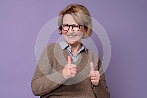 Caucasian happy senior woman showing her two thumbs up approving choice