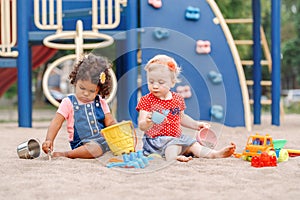 Caucasian and hispanic latin babies children sitting in sandbox playing