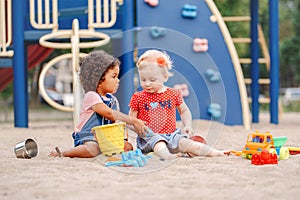 Caucasian and hispanic latin babies children sitting in sandbox playing