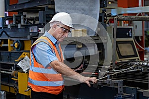 Caucasian industrial worker is using laptop computer to calibrating machine while inspecting inside the metal sheet galvanized roo