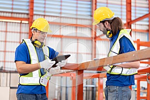 Caucasian iron welding workers with tablet in front of the red steel structure