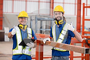 Caucasian iron welding workers with tablet in front of the red steel structure