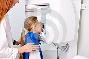 kid girl patient doing panoramic teeth x-ray orthopantomography in clinic photo