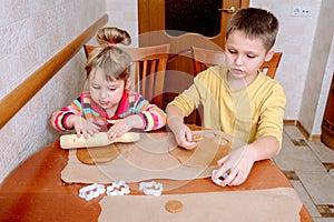 Caucasian kids cuts flattened dough into shapes. Process of making forms biscuits or gingerbread. Family activity at home.