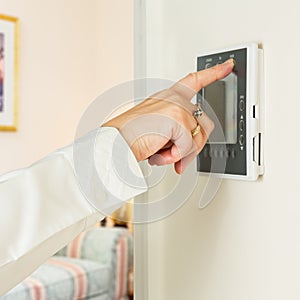 Caucasian lady pressing modern thermostat