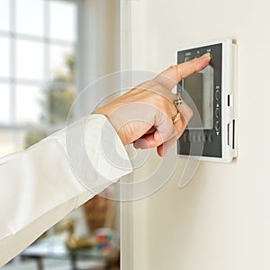 Caucasian lady pressing modern thermostat