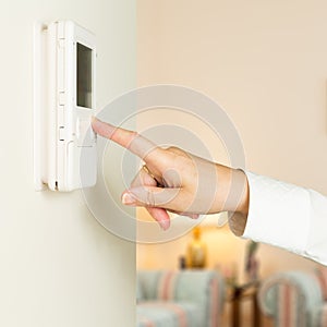 Caucasian lady pressing modern thermostat