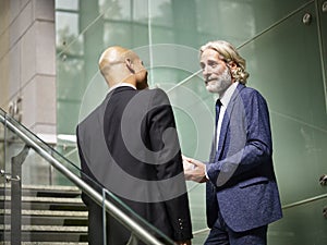 Caucasian and latino business men having a conversation while walking on stairs in modern office building