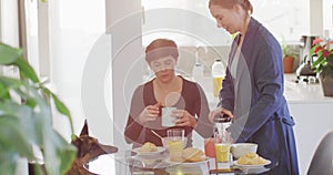 Caucasian lesbian couple having breakfast together in the living room at home