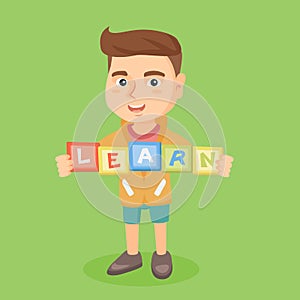 Boy holding blocks that spelling the word learn.