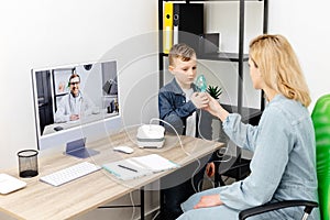 Caucasian little boy making inhalation with nebulizer at home. A young mother helping her son to inhale with a nebulizer at an