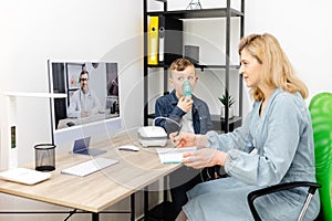 Caucasian little boy making inhalation with nebulizer at home. A young mother helping her son to inhale with a nebulizer at an