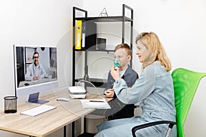 Caucasian little boy making inhalation with nebulizer at home. A young mother helping her son to inhale with a nebulizer at an