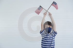 A Caucasian little boy wear mask to protect virus outbreak while holding american flag