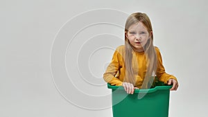 Caucasian little girl in dustbin looking at camera