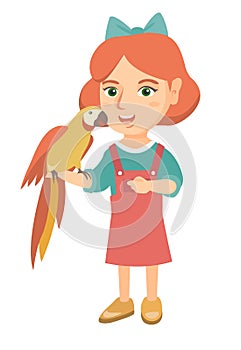 Caucasian little girl holding parrot on her hand.