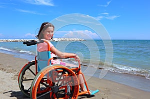 Caucasian little girl on the wheelchair on the beach