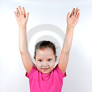 Caucasian little smiling girl raising her hands up on white background. Sport, physical training, physical jerks, healthy