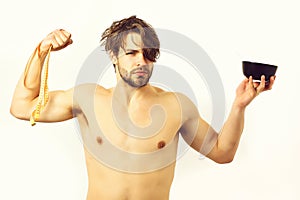 Caucasian macho holding black bowl with pasta and measuring tape