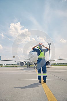 Caucasian male airport worker signaling the pilot