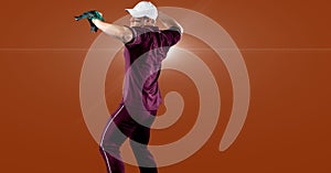 Caucasian male baseball pitcher throwing the ball against spot of light on orange background