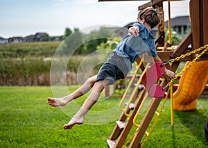Caucasian male boy jumping from a swing set in midair falling