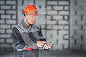 Caucasian male construction worker in overalls using smartphone