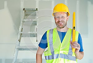 Caucasian Male Contractor With Hard Hat, Level and Safety Vest At Construction Site