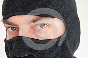 Caucasian male face wearing a black fabric ski mask. Close up shot, unrecognizable