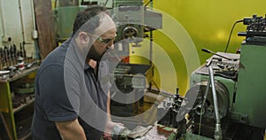 Caucasian male factory worker at a factory sitting at a workbench and operating machinery