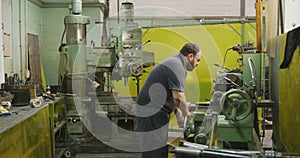 Caucasian male factory worker at a factory sitting at a workbench and operating machinery