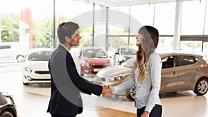 Caucasian male and female shaking hands in a car distributor