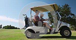 Caucasian male golfers into a golf buggy