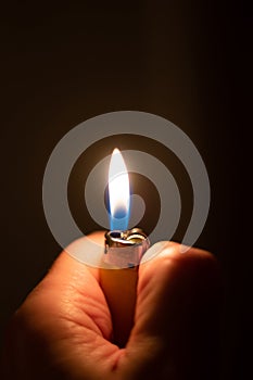 Caucasian male hand holding a lit plastic yellow  lighter close up shot isolated on black