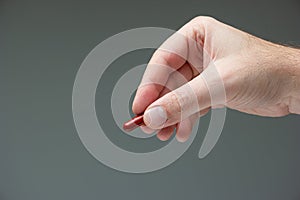 Caucasian male hand holding a red medicine capsule pill between fingers close up shot isolated studio shot