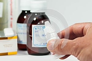 Caucasian male hand holding small medical bottle, reading the label,