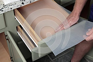 Caucasian Male Hands Placing Plastic Drawer Liner in a Bathroom