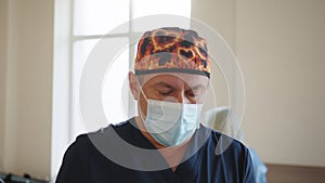 Caucasian male healthcare professional in a hospital operating theatre wearing a surgical cap and mask. Physician in Lab