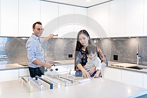 Caucasian male interior designer  demonstrating cabinet and door handle pulls for kitchen renovation remodel. East Asian female