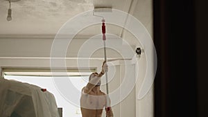 Caucasian male makes reformations in his recently bought house with paint roller