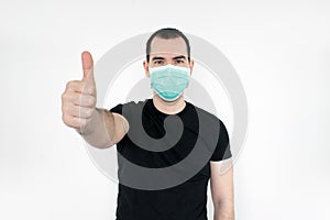 Caucasian male man young. standat white background, wear mask on face,   thumbs up gesture one hand,  protect yourself, safe peopl