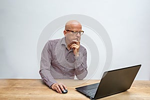 Caucasian male middle aged and with glasses, sitting behind a desk working with his lap top