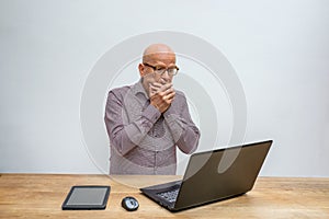 Caucasian male middle aged and with glasses, sitting behind a desk working with his lap top