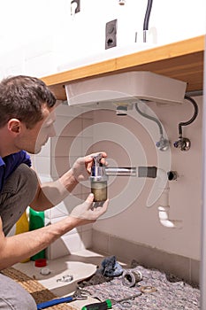 Caucasian male plumber fixing a sink in the bathroom