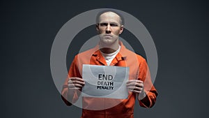 Caucasian male prisoner holding End death penalty sign in cell, asking for help