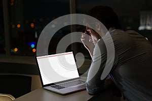 Caucasian male programmer sitting at desk, using laptop with coding on screen