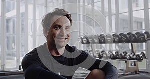 Caucasian male with prosthetic leg smiling at camera. Disabled athlete working out in a modern-style gym.