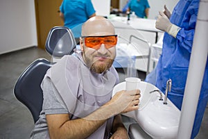 Caucasian male is rinsing his mouth during a wisdom tooth extraction surgery in a dental hospital